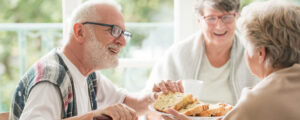 Gut gelaunte Senioren (zwei Frauen und ein Mann) beim Kuchen essen