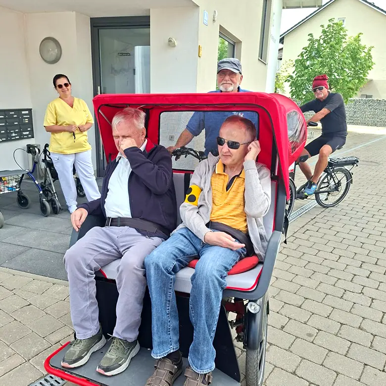 Zwei Herren sitzen in einer Fahrrad-Rikscha