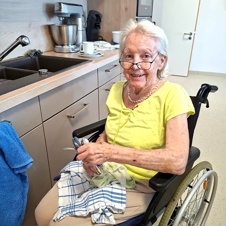 Dame im Rollstuhl trocknet Besteck ab
